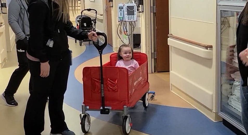 Hospitalized child riding in Starlight Radio Flyer Hero Wagon through hospital hallways.